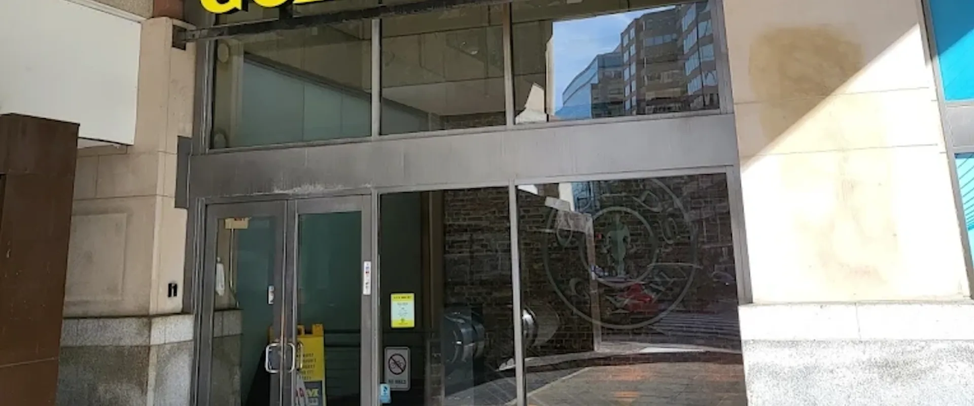 Exterior of Gold’s Gym Dupont Circle with yellow logo above glass doors in a downtown city setting.