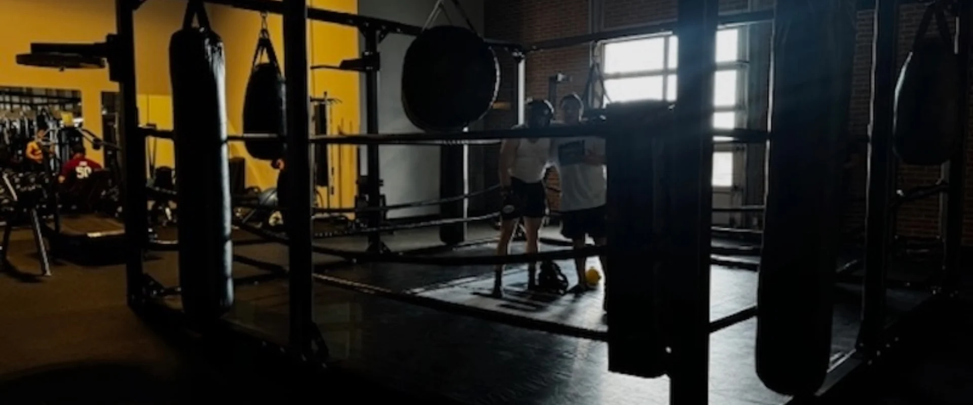 Boxing ring with hanging punching bags and training space.