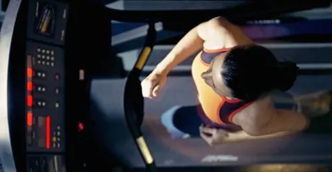 The image depicts a person in a revealing outfit, sitting in front of a computer screen displaying various data visualizations.