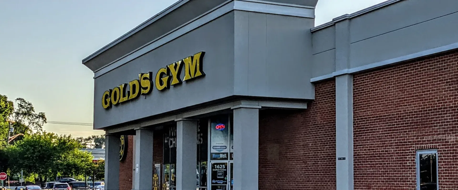 Exterior of Gold’s Gym Crofton with yellow logo above entrance on a brick and gray building.
