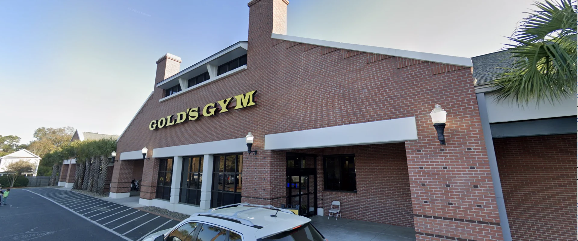 Exterior of Gold’s Gym Mt. Pleasant with red brick walls, white trim, and yellow Gold’s Gym signage above the entrance.