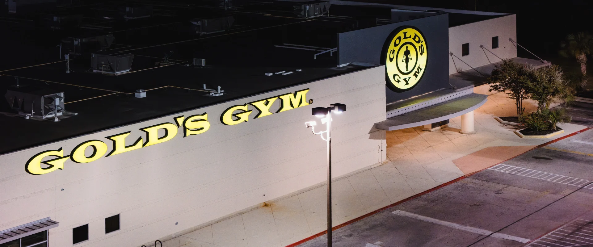The Gold’s Gym Valley Hi exterior captured at night, featuring the bright yellow logo and clean modern facade that represents the gym’s legacy of strength and community.