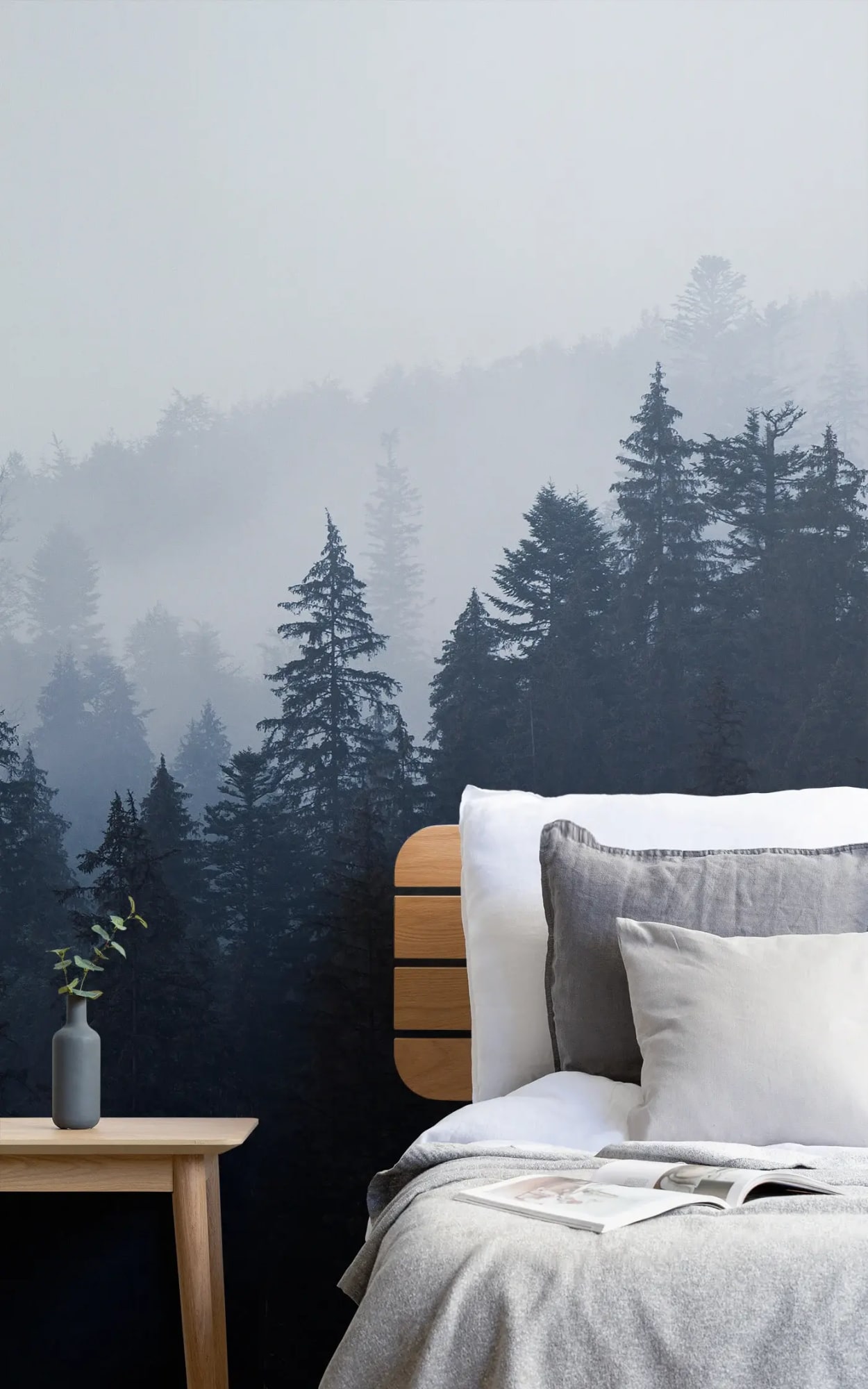 The room is serene, featuring a mural of a foggy, dense forest that stretches across the wall, providing a tranquil backdrop for the simple and elegant bedside setup.