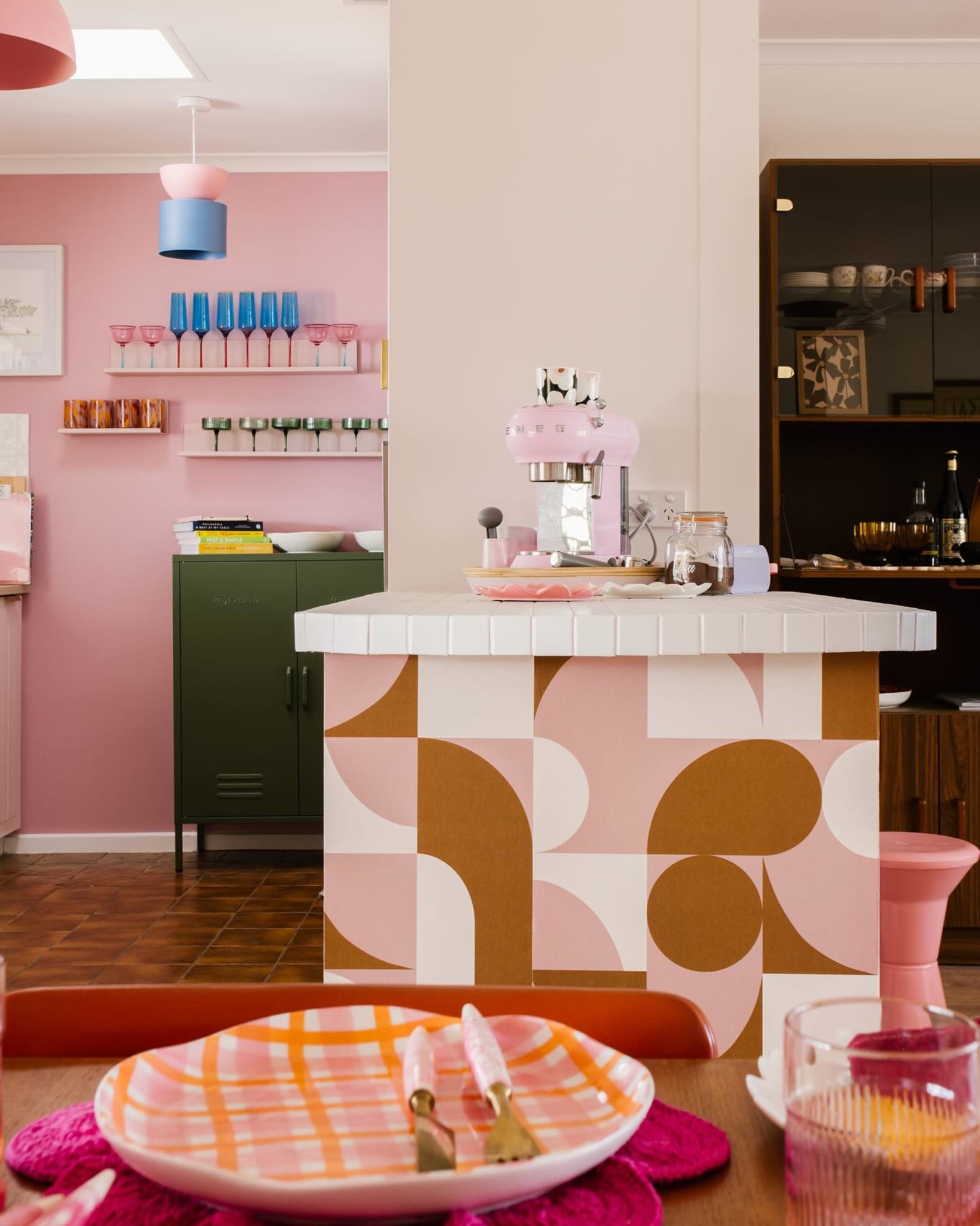 Retro-inspired kitchen with a tiled island covered in pink and tan geometric wallpaper.