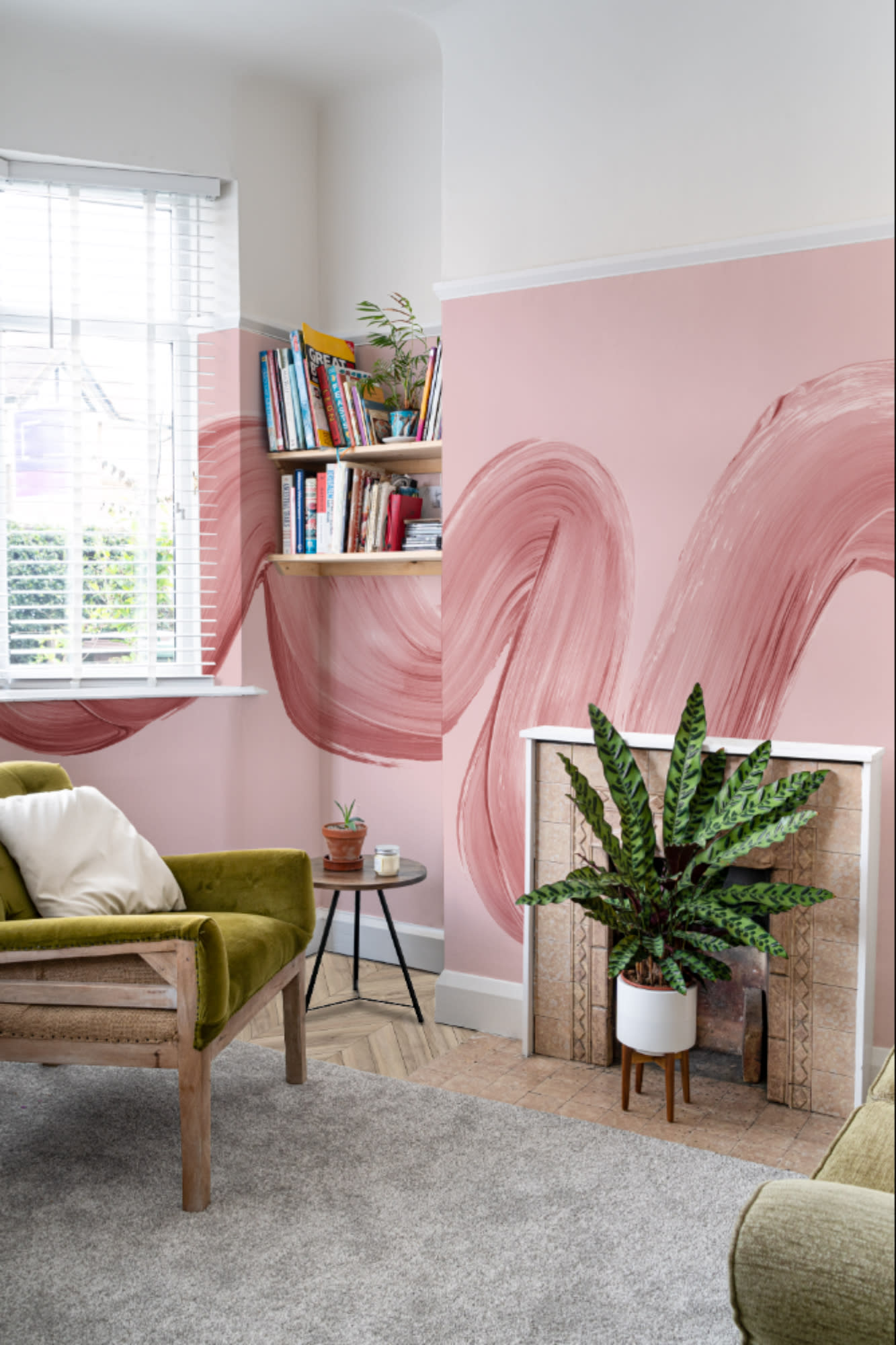 A pink living room features a bold brushstroke mural wrapping around the chimney breast and corner wall.