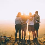 Photo of four people with their arms around each other by Helena Lopes on Unsplash