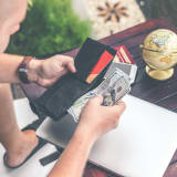 Photo of a man pulling money out of his wallet by Artem Beliaikin on Unsplash