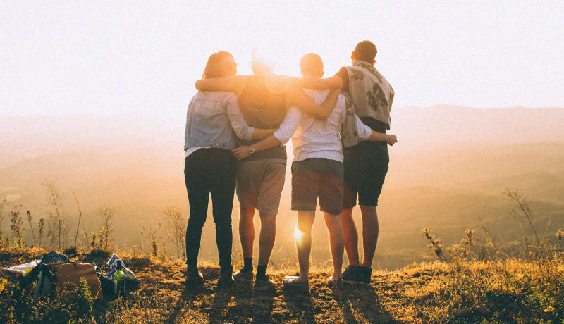 Photo of four people with their arms around each other by Helena Lopes on Unsplash