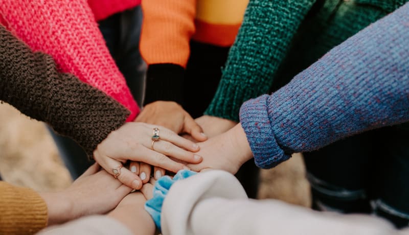 Photo of people's hands in a huddle by Hannah Busing on Unsplash