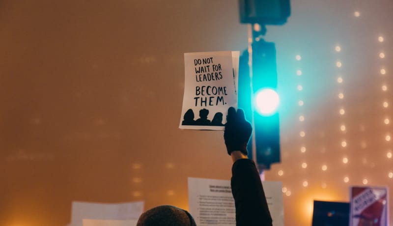 Photo of a hand holding up a sign that says 'Do not wait for leaders, become them' by Rob Walsh on Unsplash