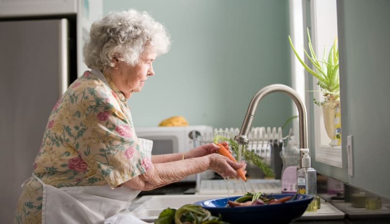 Photo of an elderly lady washing vegetables in the sink by CDC on Unsplash