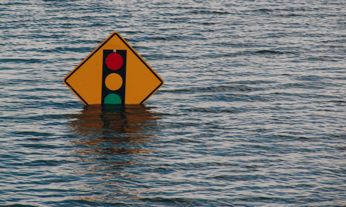 Photo of a traffic sign covered by flood waters by Kelly Sikkema on Unsplash