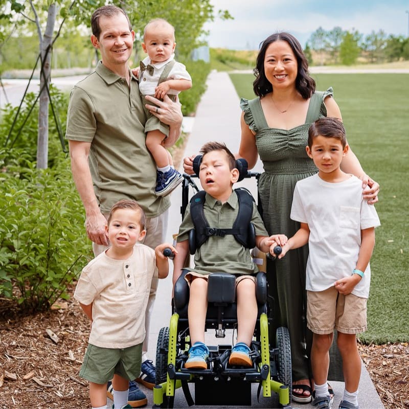 A man and woman standing around 4 young boys, one in a wheelchair