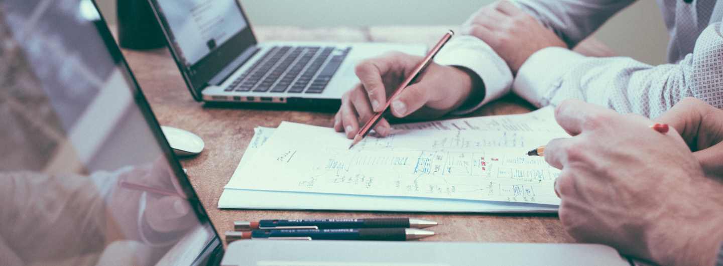 laptop na stolu, ljudi gledaju u ekran 