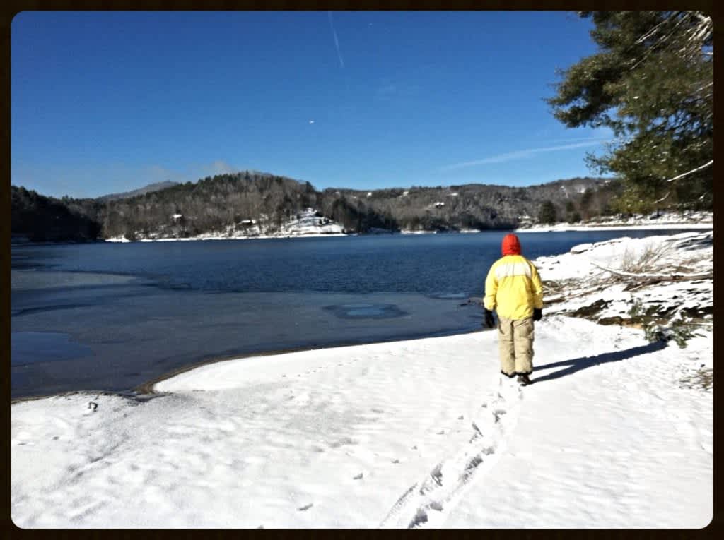 Man walking in snow next to Lake Glenville, NC