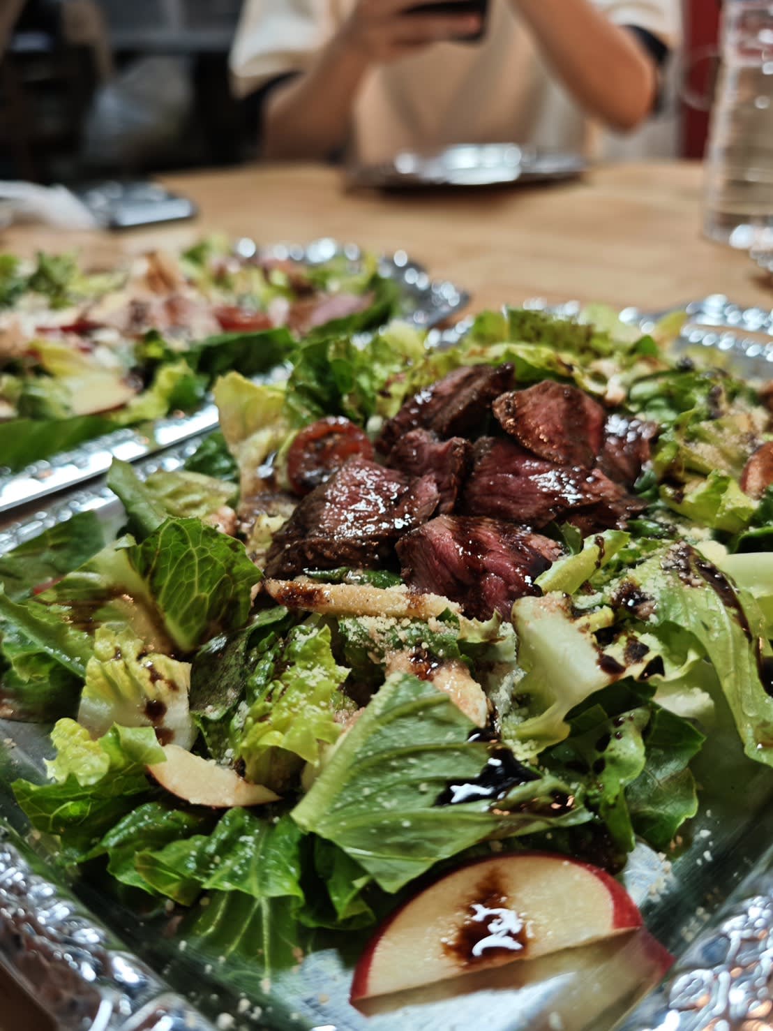 Sliced grilled beef with salad greens and fresh tomato, drizzled with balsamic glaze — the sweet-tart note cuts through the beef's richness perfectly. A clean starter that's anything but bland.