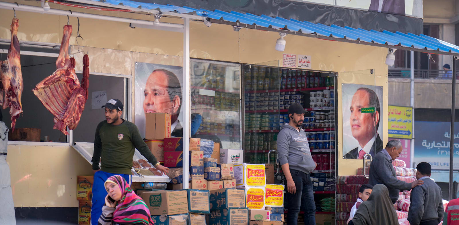 לקוחות בקהיר קונים מצרכים בחנות מעוטרת בפוסטרים של נשיא מצרים א־סיסי / צילום: Associated Press
