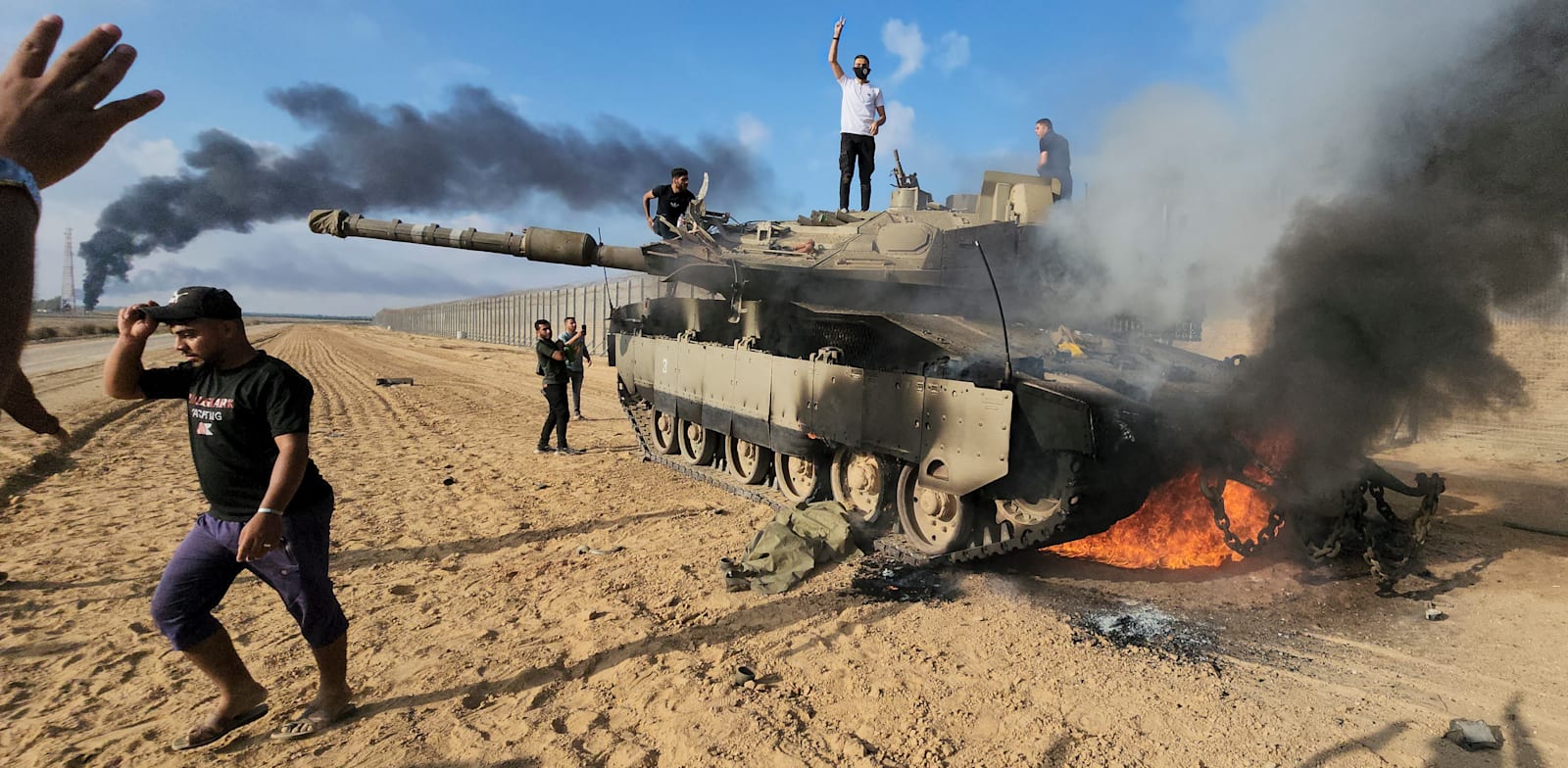 מחבלים שנכנסו לישראל דרך גדר ההפרדה הפרוצה חוגגים על טנק הרוס של צה''ל בחאן יונס / צילום: ap, Hassan Eslaiah