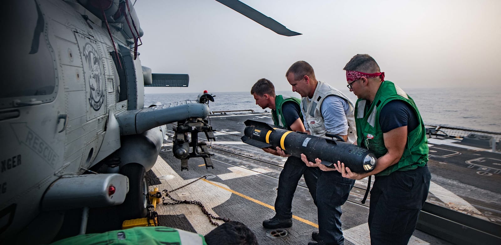 "MH-60R Sea Hawk לוחמי הצי האמריקאי מעמיסים טיל על מסוק / צילום: Reuters, ABACA"