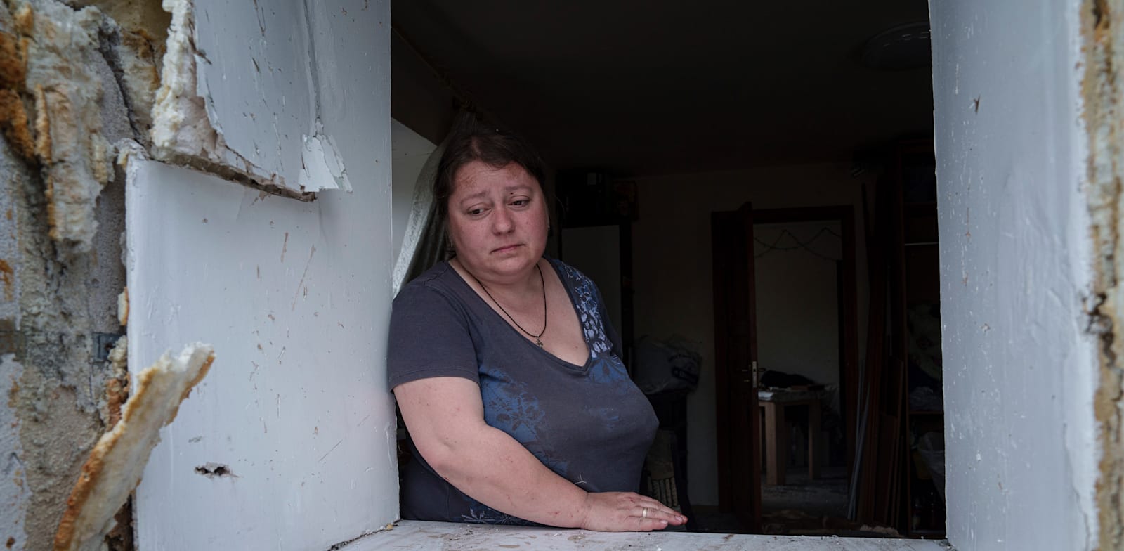 אישה שביתה נהרס במתקפה רוסית מסתכלת על שכונת מגוריה שרובה הותקפה / צילום: ap, Evgeniy Maloletka