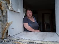 אישה שביתה נהרס במתקפה רוסית מסתכלת על שכונת מגוריה שרובה הותקפה / צילום: ap, Evgeniy Maloletka
