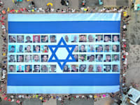 דגל ישראל עם תמונות החטופים נפרש היום בכיכר החטופים / צילום: Reuters, Anadolu
