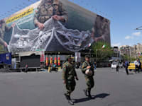 שני שוטרים בטהרן הולכים מול שלט המתאר את המטוסים האמריקאים נופלים לתוך הרשת של משמרות המהפכה / צילום: ap, Vahid Salemi