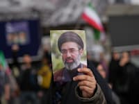 מפגין איראני מחזיק בתמונה של מוג'תבא חמינאי / צילום: ap, Francisco Seco