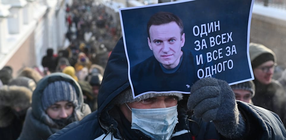 מפגין אוחז בשלט עם תמונתו של אלכסיי נבלני והכיתוב "אחד בשביל כולם, כולם בשביל אחד" / צילום: Reuters, Alexey Malgavko