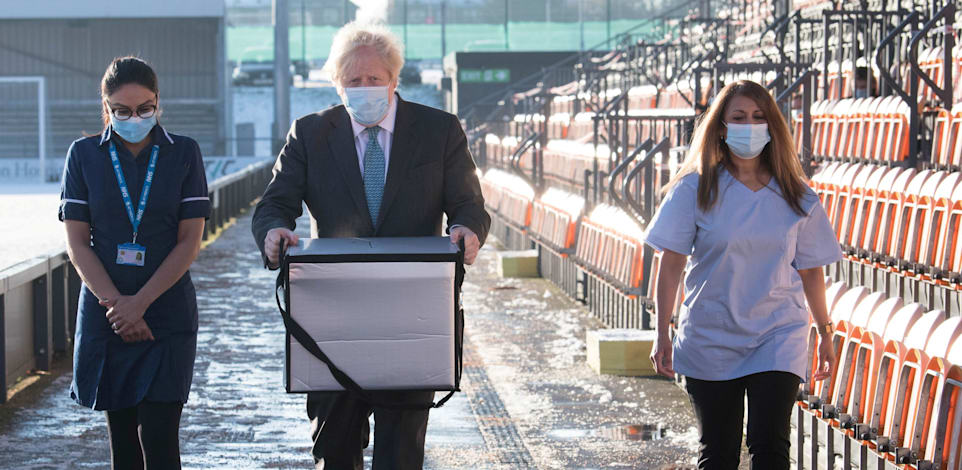 בוריס ג'ונסון מחזיק בקופסה עם חיסוני אסטרהזנקה במרכז חיסונים בלונדון / צילום: Reuters, Stefan Rousseau