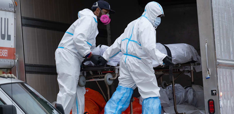 עובדים מעבירים גופה של אדם שמת מקורונה למשאית קירור לאחר שלא נשאר מקום בבית הלווית, ניו יורק באפריל 2020 / צילום: Associated Press, Craig Ruttle