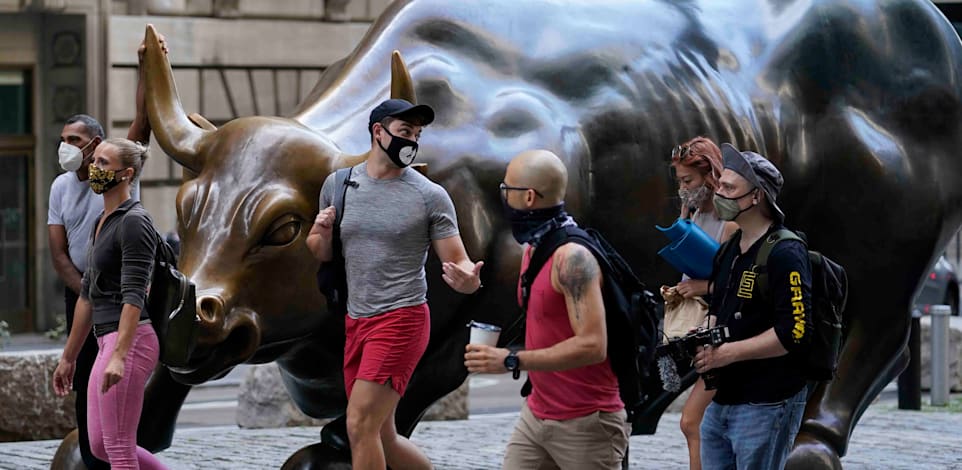 צעירים חולפים על פני פסל השור בוול סטריט, ניו יורק / צילום: Associated Press, Mark Lennihan