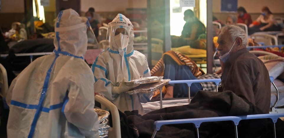 צוות רפואי עובר בין החולים במרכז בידוד בניו דלהי. הצוותים הרפואיים קורסים תחת עומס החולים ברחבי המדינה / צילום: Associated Press, Manish Swarup