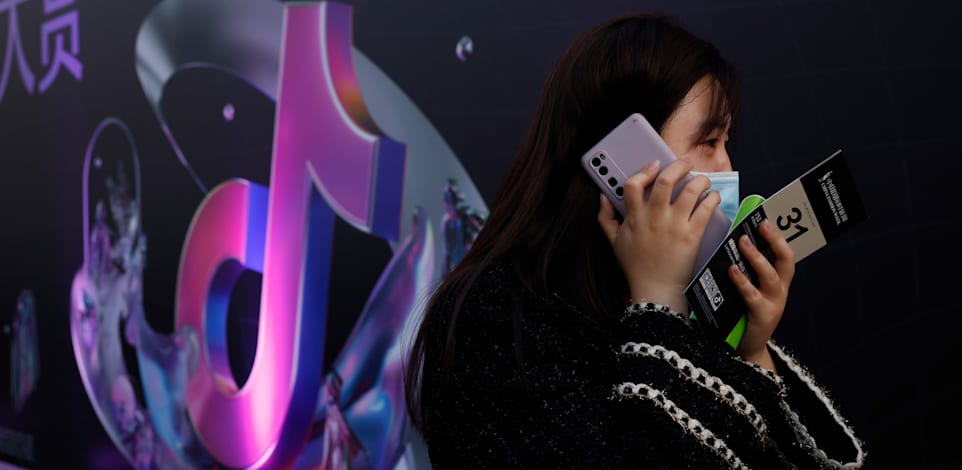אישה משוחחת בטלפון ברחובות בייג'ינג / צילום: Associated Press, Ng Han Guan