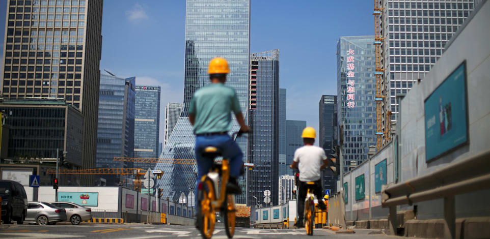 פועלי בניין רוכבים על אופניים בדרך לעבודה ליד מטה אוורגרנד בשנזן / צילום: Reuters, CARLOS GARCIA RAWLINS