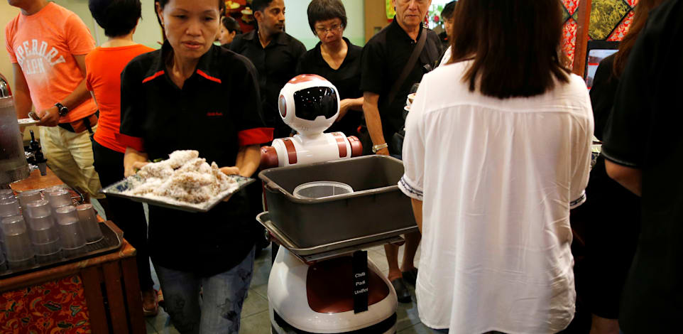 רובוט ומלצרית מנווטים את דרכם לאסוף כלים מלוכלכים במסעדה בסינגפור, 2016 / צילום: Reuters, Edgar Su