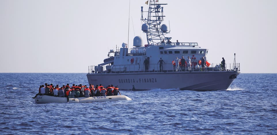 כוחות איטלקיים לצד סירת מהגרים, בסמוך לאי למפדוזה / צילום: Reuters, Juan Medina