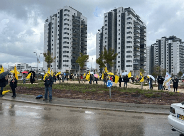 עם דגלי ישראל ודגלים צהובים, עשרות מחברי קהילת ניר עוז עומדים הבוקר במחאה שקטה ליד מקום מגוריהם הזמני בכרמי גת Share / צילום: N12 עם דגלי ישראל ודגלים צהובים, עשרות מחברי קהילת ניר עוז עומדים הבוקר במחאה שקטה ליד מקום מגוריהם הזמני בכרמי גת Share / צילום: N12