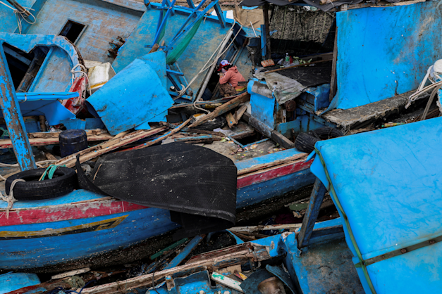 אישה בין ספינות דיג שנשטפו לחוף על ידי טייפון במחוז דאק לק, וייטנאם, השבוע / צילום: Reuters, Minh Nguyen