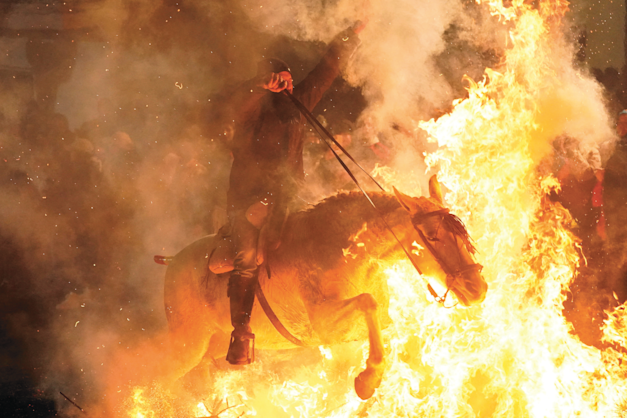 אדם רוכב דרך מדורה בחגיגת יום אנטוניוס הקדוש, פטרון בעלי החיים, ספרד, השבוע / צילום: Reuters, Ana Beltran