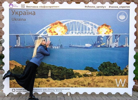 A Ukrainian woman near the design of the special stamp that will be issued by the Post Office in honor of the Crimean bridge explosion / Photo: Reuters, Stringer