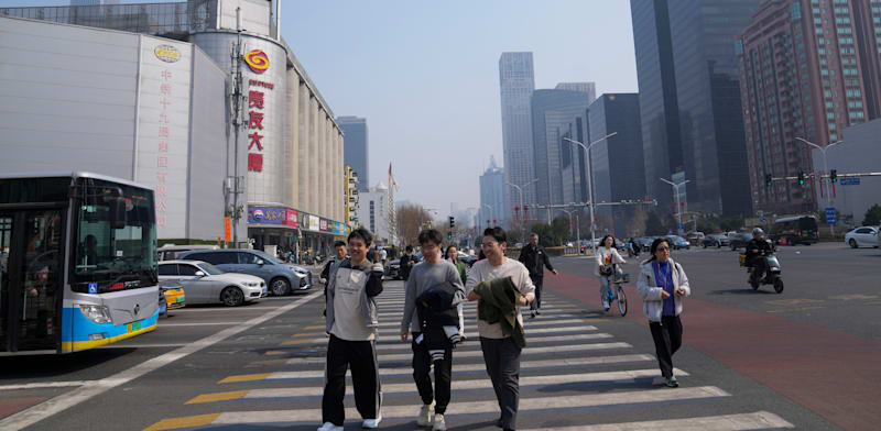 צעירים עוברים ברובע העסקי בבייג'ין / צילום: ap, Tatan Syuflana