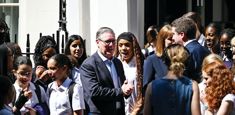 "קיר סטראמר, ראש ממשלת בריטניה, לצד תלמידי תיכון. רוצה להרחיב את  בסיס הבוחרים / צילום: Reuters, Chris J Ratcliffe"