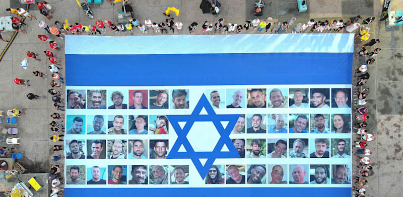 דגל ישראל עם תמונות החטופים נפרש היום בכיכר החטופים / צילום: Reuters, Anadolu