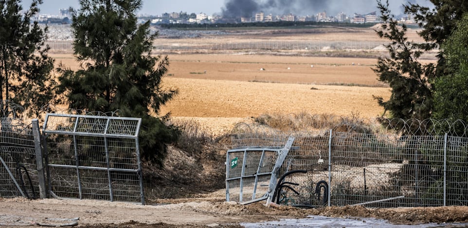 גדר ההפרדה פרוצה כשעזה ברקע / צילום: Reuters, Ilia Yefimovich