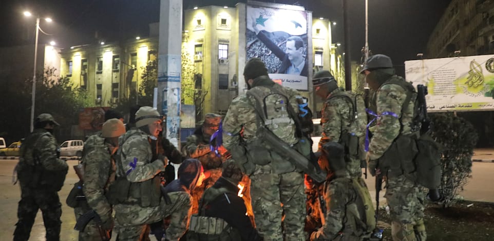 המורדים הסורים מתחממים סביב מדורה שהקימו לאחר ההשתלטות מחדש על מחוז אלפו שבסוריה / צילום: Reuters, MAHMOUD HASANO