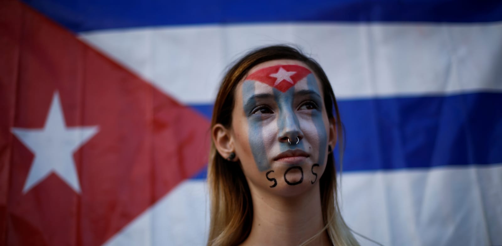 אישה מפגינה נגד הממשל בקובה ליד ארגון ההגירה הבינלאומי במקסיקו / צילום: Reuters, Jose Luis Gonzalez