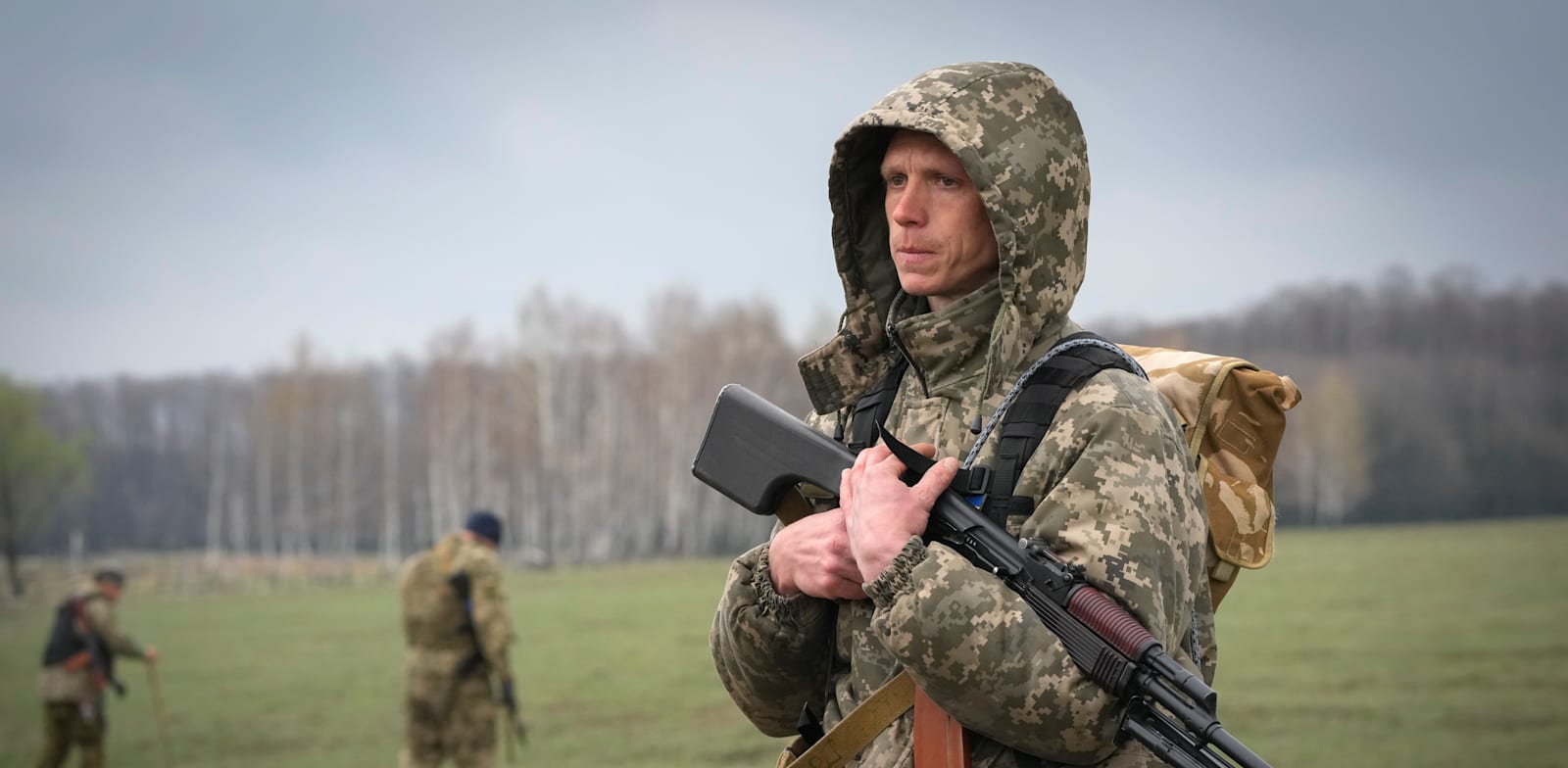 חייל אוקראיני עומד בשדה שבו חבריו מחפשים מוקשים שהשאירו הרוסים בכפר ברזובקה / צילום: Associated Press, Efrem Lukatsky