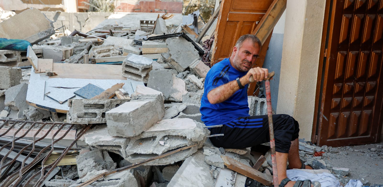 תושב עזה בין ההריסות / צילום: Reuters, IBRAHEEM ABU MUSTAFA