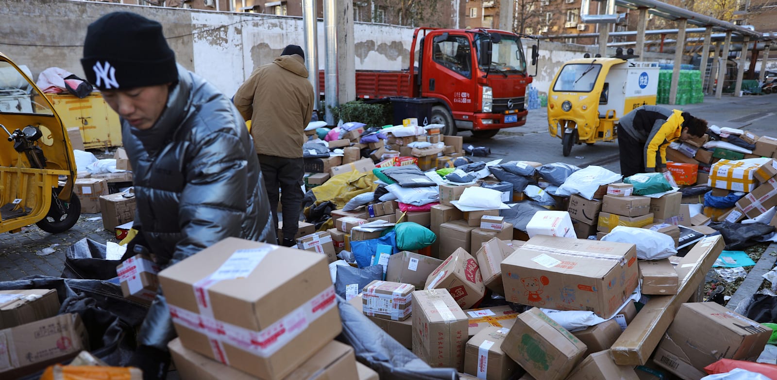 עובדי שילוח ממיינים חבילות דואר, דצמבר 2021 / צילום: Reuters, TINGSHU WANG